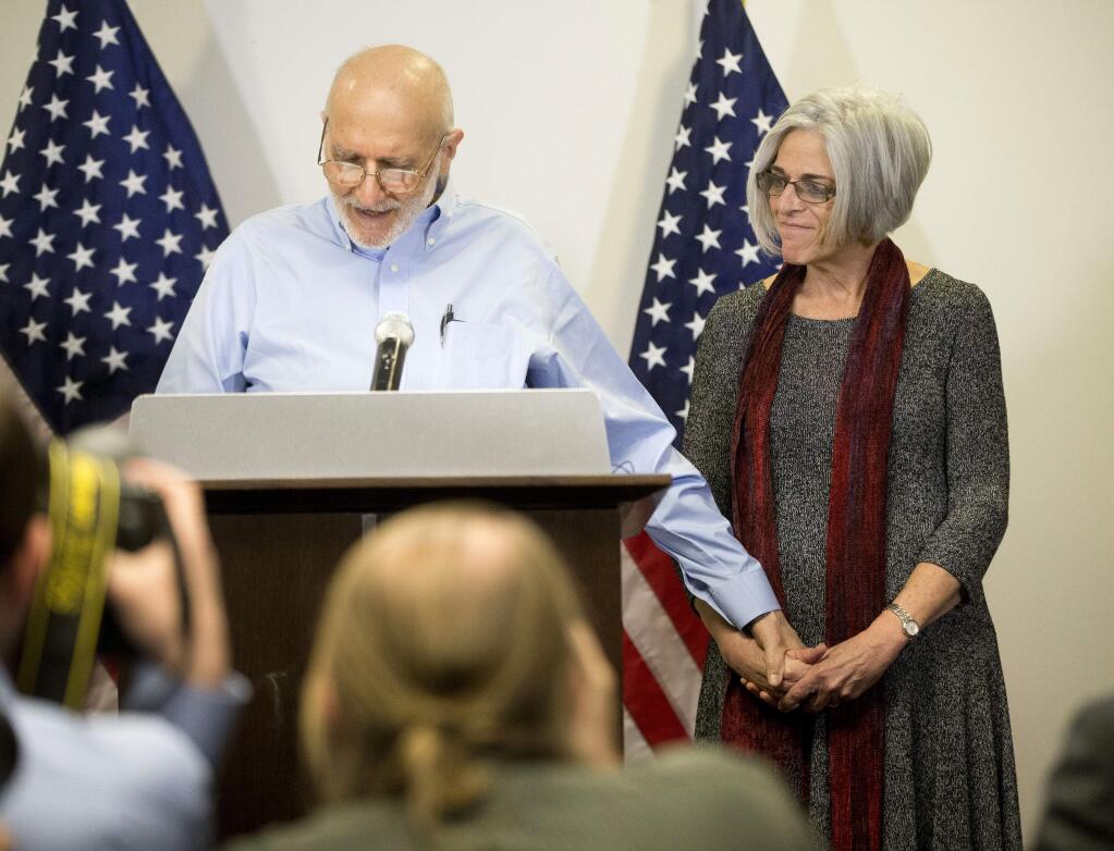 Alan Gross holds his wife Judy's hand while during a news conference at his lawyer's office in Washington, Wednesday, Dec. 17, 2014. Gross was released from Cuba after 5 years in a Cuban prison. (AP Photo/Pablo Martinez Monsivais)
