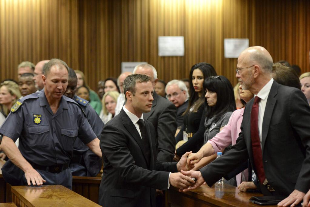 Oscar Pistorius, center, greets his uncle Arnold Pistorius, right, and other family members as he is led down to the cells of the court in Pretoria, South Africa, Tuesday, Oct. 21, 2014. Pistorius received a five-year prison sentence for culpable homicide by judge Thokozile Masipais for the killing of his girlfriend Reeva Steenkamp last year (AP Photo/Herman Verwey, Pool)