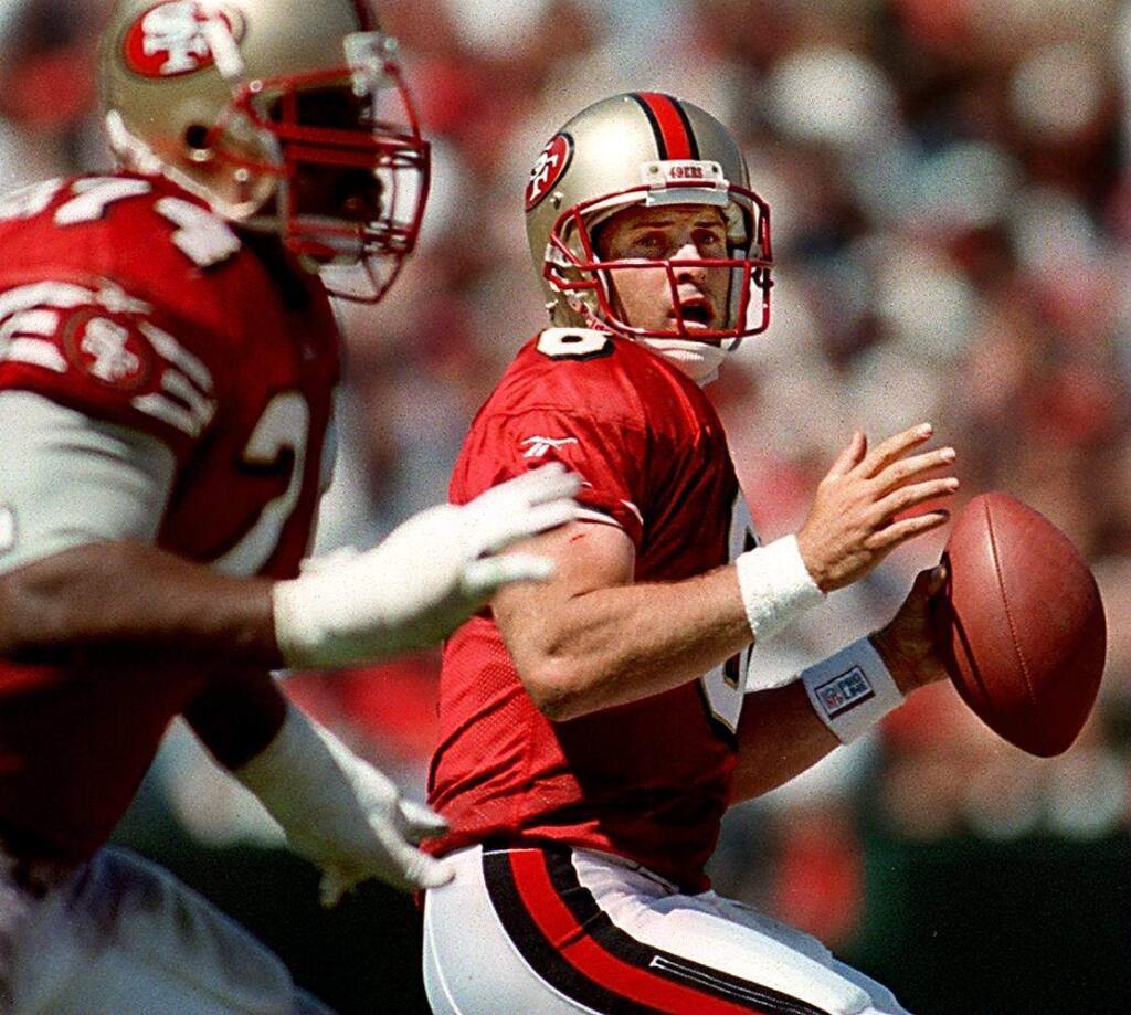 Steve Young looks for a reciever in the 49ers victory over the Rams, as Steve Wallace blocks. Local photos sports