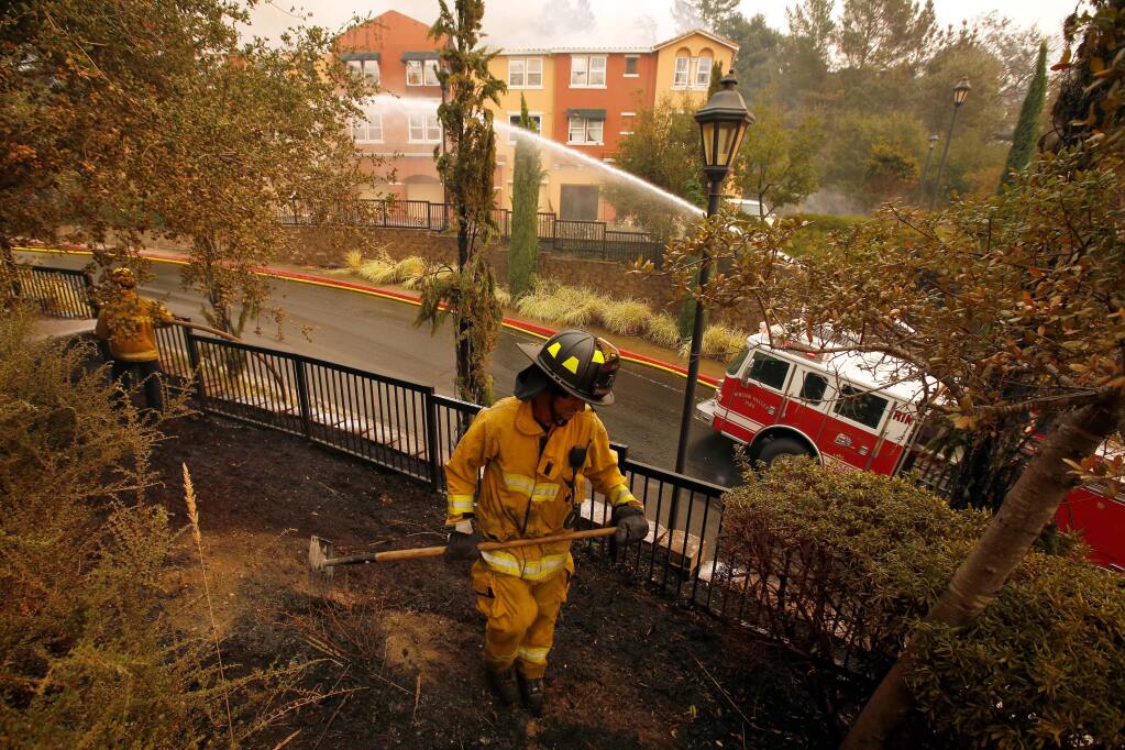 Rincon Valley fire engineer Nate DeJung, center, and other firefighters extinguish fires around The Overlook apartments at Fountaingrove after the Tubbs Fire burned through north Santa Rosa, California on Monday, October 9, 2017. (Alvin Jornada / The Press Democrat)