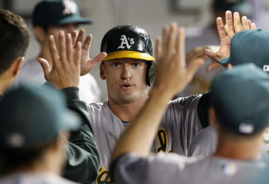 Oakland Athletics' Josh Donaldson celebrates in the dugout after scoring on a ground out by Derek Norris during the fourth inning of a baseball game against the Chicago White Sox on Tuesday, Sept. 9, 2014, in Chicago. (AP Photo/Charles Rex Arbogast)
