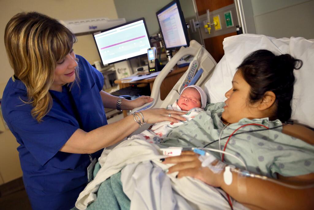 Registered nurse Rebecca Moore checks in on Regina Vaca and her newborn, Jordan Chase Smith, in a birthing suite at Sutter Santa Rosa Regional Hospital, on Tuesday, March 31, 2015. (Christopher Chung/ The Press Democrat)