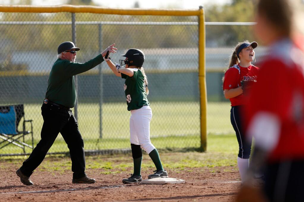 Casa Grande assistant coach Don White high-fives Skylar Thorpe after she hit a triple with one RBI during the fourth inning of a varsity softball game between Casa Grande and Rancho Cotate high schools in Rohnert Park on Thursday, April 12, 2018. (Alvin Jornada / The Press Democrat)