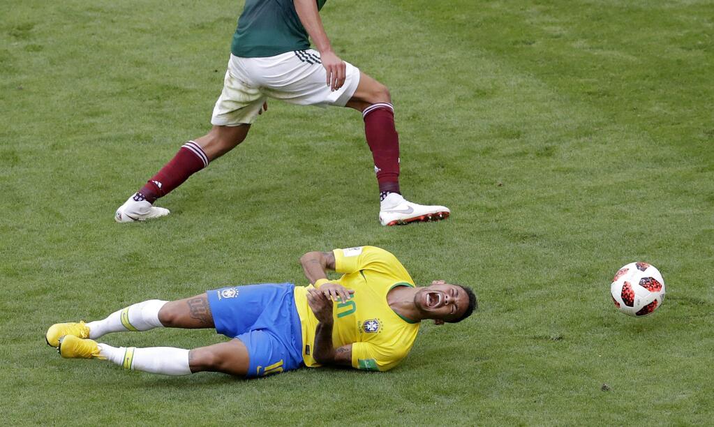 Brazil's Neymar, bottom, lies on the field during the round-of-16 match between Brazil and Mexico at the 2018 soccer World Cup at the Samara Arena, in Samara, Russia, Monday, July 2, 2018. (AP Photo/Sergei Grits)