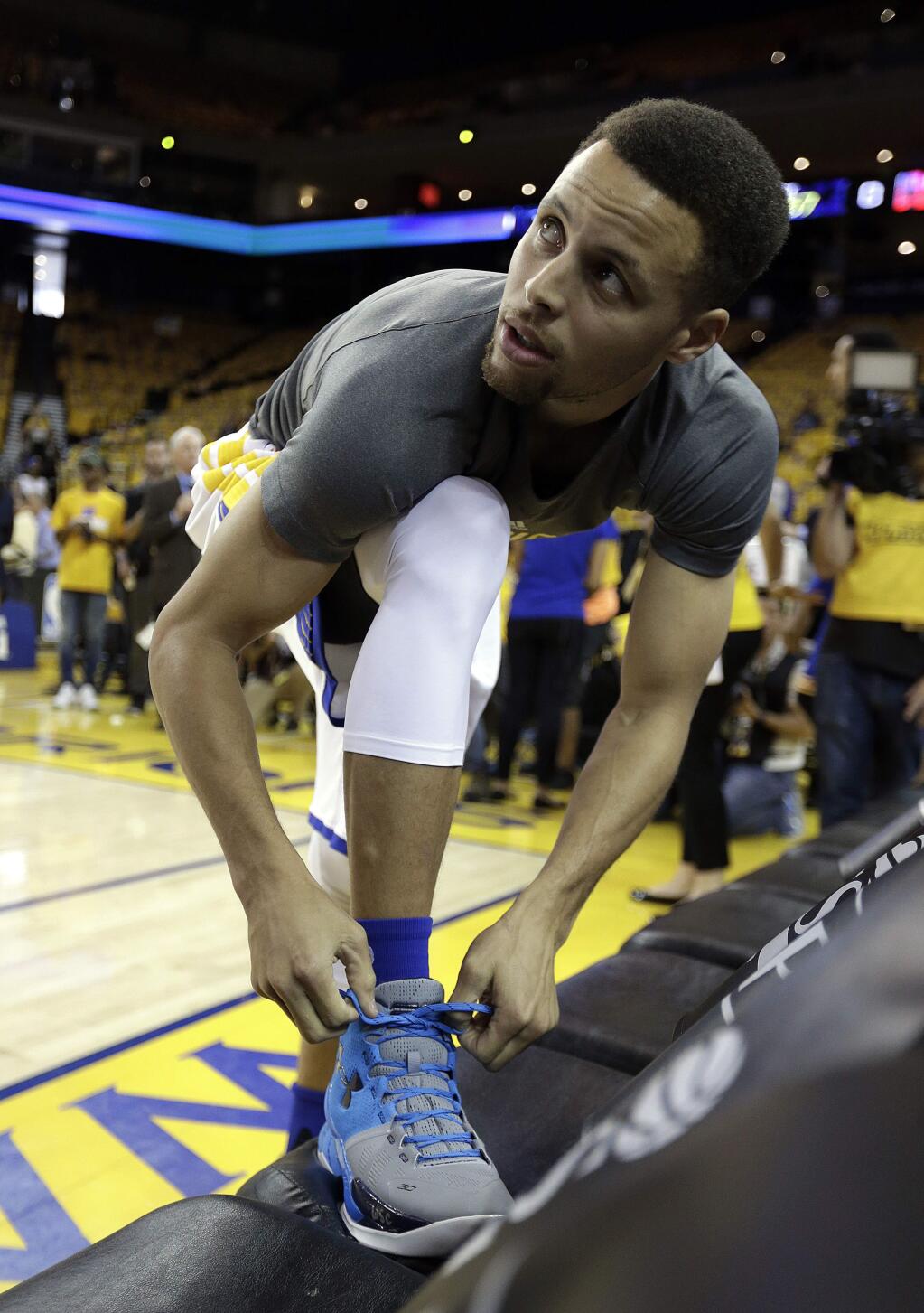 Golden State Warriors' Stephen Curry laces up his right shoe during a warm up prior to Game 2 of a first-round NBA basketball playoff series against the Houston Rockets on Monday, April 18, 2016, in Oakland, Calif. (AP Photo/Ben Margot)