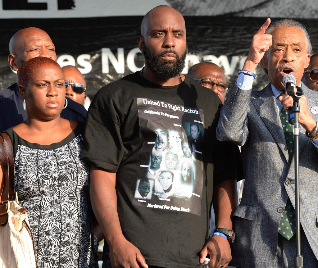 Reverend Al Sharpton, right, introduces the father of slain teen Michael Brown, Michael Brown, Sr., center to the crowd at Peace Fest, Sunday, Aug. 24, 2014, in St. Louis. 'Tomorrow all I want is peace,' Brown Sr. told hundreds of people in St. Louis largest city park Sunday during brief remarks at a festival that promoted peace over violence. (AP Photo/Bill Boyce)