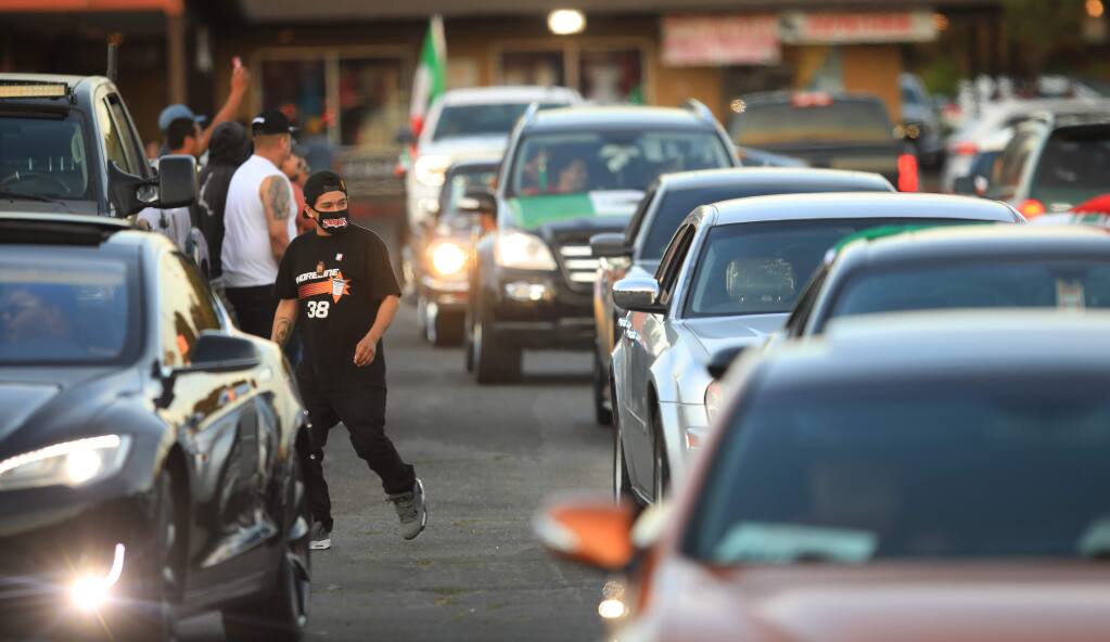 Dozens of people in vehicles cruise the parking lot next to the Dollar Tree in Roseland, Tuesday May 5, 2020. (Kent Porter / The Press Democrat) 2020