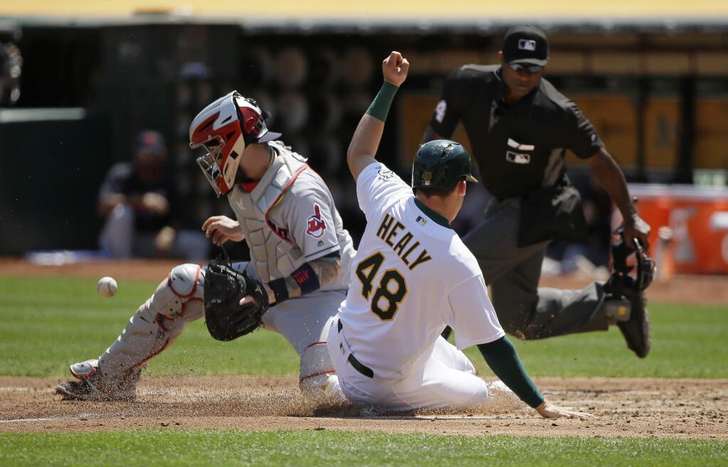 Oakland Athletics' Ryon Healy slides safely into home plate to score the Athletics' third run as Cleveland Indians catcher Roberto Perez waits for the throw in the second inning Wednesday, Aug. 24, 2016, in Oakland. In the background is home plate umpire Alan Porter. Healy scored after the Athletics' Chad Pinder hit a sacrifice fly to right field. (AP Photo/Eric Risberg)