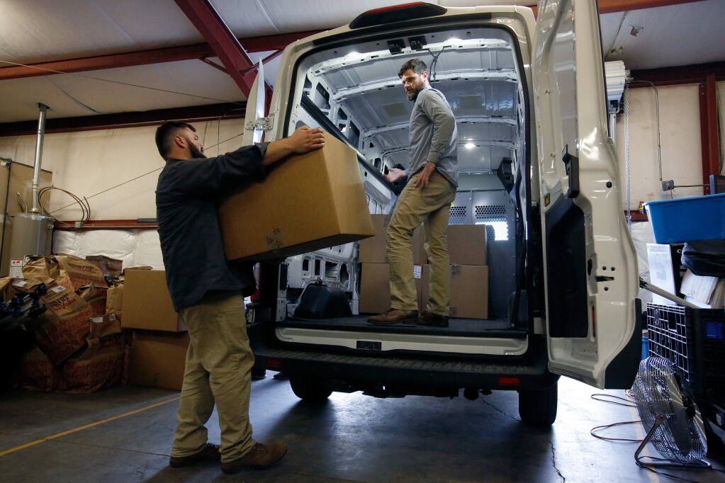 Old Kai Distribution cofounders Matthew Mandelker, left, and Lucas Seymour, who are licensed cannabis distributors, load a delivery van with boxes of their product at their warehouse near Ukiah, California on Tuesday, December 26, 2017. Despite having a Mendocino County cannabis license, a vanload of product from Old Kai Distribution was seized by CHP during a traffic stop of one of their delivery vehicles. (Alvin Jornada / The Press Democrat)