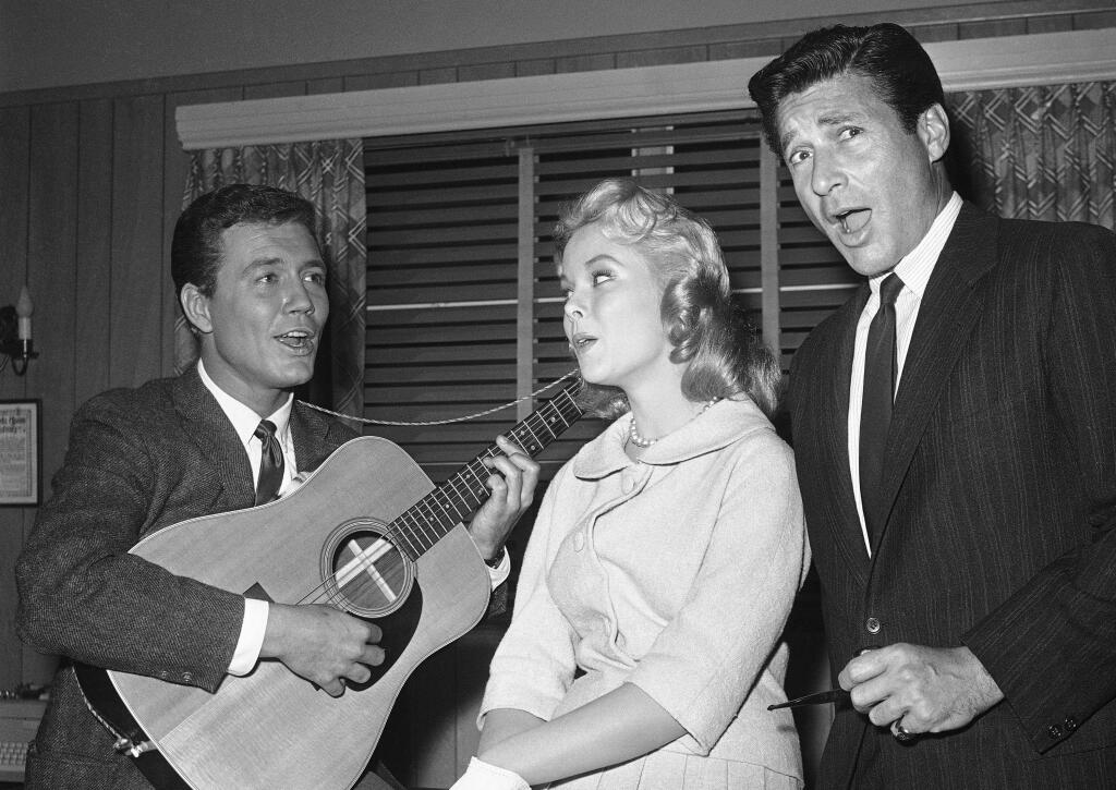 FILE - In this Feb. 15, 1961 file photo, actors Roger Smith, from left, Carolyn Komant and Efrem Zimbalist Jr., tune up for their parts in the TV series '77 Sunset Strip,' in Los Angeles. Smith, star of the “77 Sunset Strip,” and husband of actress Ann-Margret, died at a Los Angeles hospital on Sunday, June 4, 2017, at age 84. (AP Photo/Harold Filan, File)