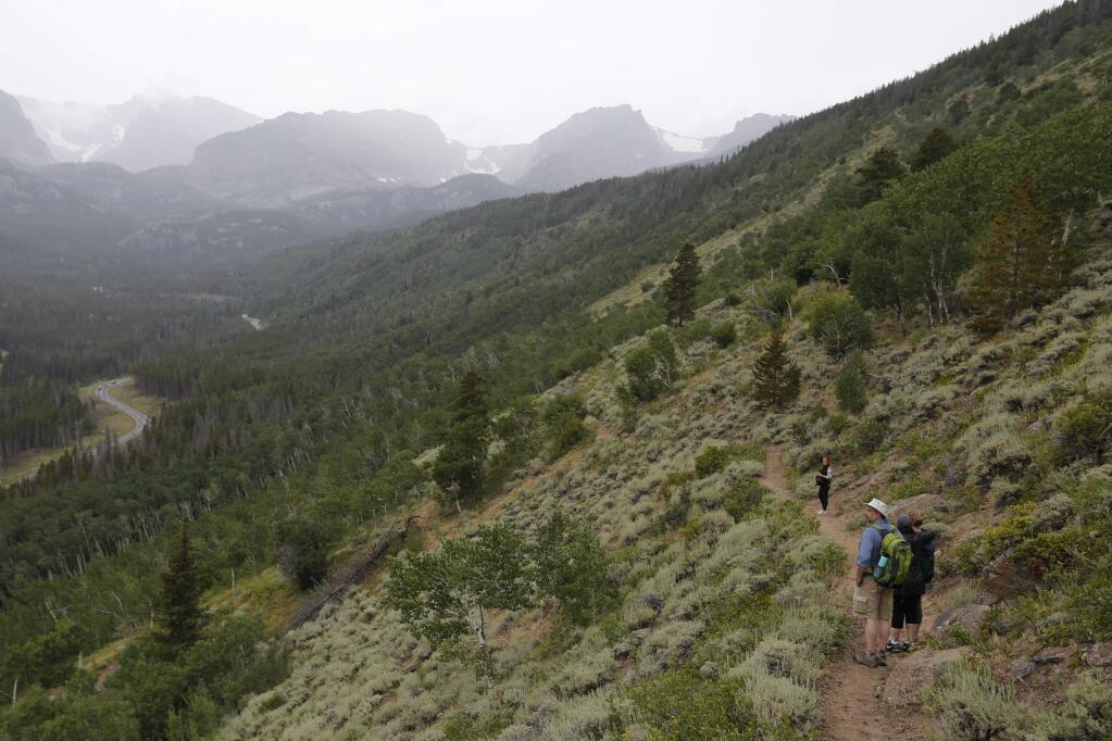In this Aug. 4, 2016 photo, hikers descend a ridge inside Rocky Mountain National Park, near Estes Park, Colo. The National Park Service celebrates its 100th birthday Thursday, Aug. 25, 2016. The federal agency oversees 131,000 square miles of parks, battlefields and other landmarks across the nation and in four U.S. territories. (AP Photo/Brennan Linsley)