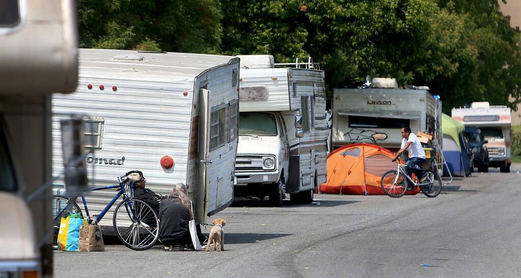 Adrienne Lauby, of Homeless Action, with dog, talks with a resident of a motor home community at the Northpoint Corporate Center in Santa Rosa, Friday, August 24, 2018 that were displaced by last years fires. Homeless Action and St. Vincent de Paul have teamed up to raise funds to help people pay their DMV registration costs for the vehicles. (Kent Porter / The Press Democrat) 2018