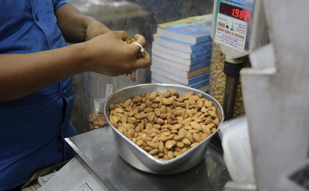 In this June 22, 2019 file photo, a shopkeeper weighs California almonds for a customer at a shop in New Delhi, India. Almonds used to have about 170 calories per serving, then researchers said it was really more like 130. A little later, they said the nuts may have even less. The shifting numbers for almonds show how the figures stamped on nutrition labels may not be as precise as they seem. (AP Photo/Altaf Qadri)