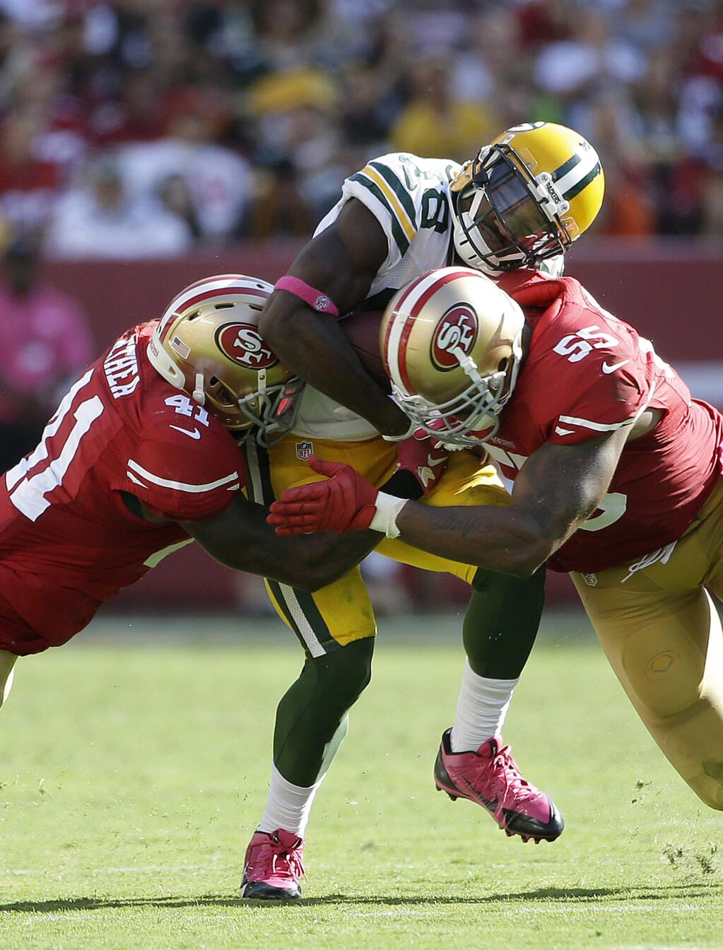 Green Bay Packers wide receiver Ty Montgomery, center, is tackled by San Francisco 49ers strong safety Antoine Bethea (41) and linebacker Ahmad Brooks (55) Sunday, Oct. 4, 2015. (AP Photo/Marcio Jose Sanchez)