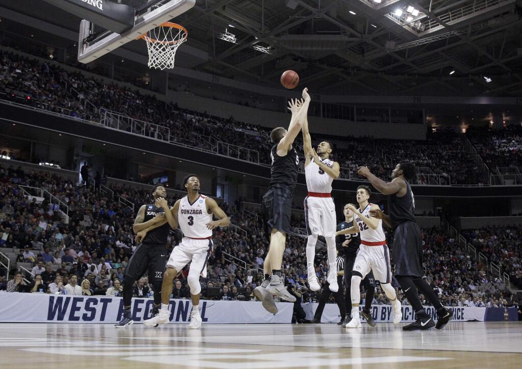 Gonzaga guard Nigel Williams-Goss, center, right, shoots over Xavier's Sean O'Mara, center left, during the first half of an NCAA Tournament college basketball regional final game Saturday, March 25, 2017, in San Jose, Calif. (AP Photo/Tony Avelar)