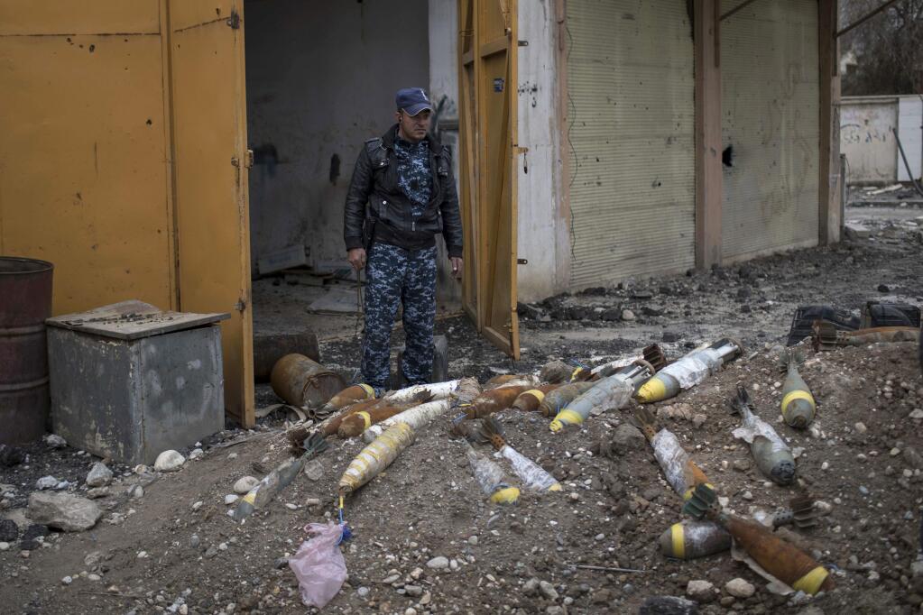 FILE- In this March 22, 2017, file photo, a Federal Police stands next to unexploded bombs left by Islamic State group militants on the western side of Mosul, Iraq. On Thursday, Aug. 17, the top U.S. commander in Iraq said for the first time that the American military will help contractors and other officials locate unexploded bombs dropped by the coalition. U.S. Embassy officials have asked the coalition to declassify grid coordinates for bombs dropped in Iraq to help clear the explosives. The coalition's unexploded bombs are only a small part of Mosul's problems. The bulk of the explosives have been hidden by IS fighters to be triggered by the slightest movement, even picking up a seemingly innocent children's toy, lifting a vacuum cleaner, or opening an oven door. (AP Photo/Felipe Dana, File)