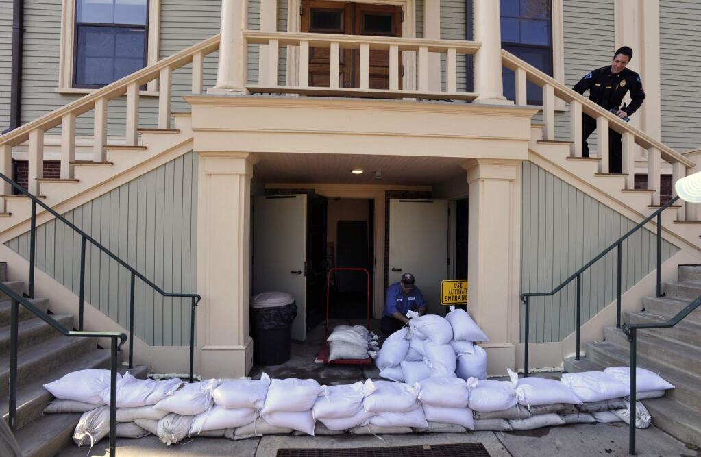 Provincetown DPW worker Paulo Andrade moves sand bags around the lower entrance to town hall as preparations are underway for the approaching storm, Thursday, March 1, 2018 in Provincetown, Mass. (Steve Heaslip/The Cape Cod Times via AP)