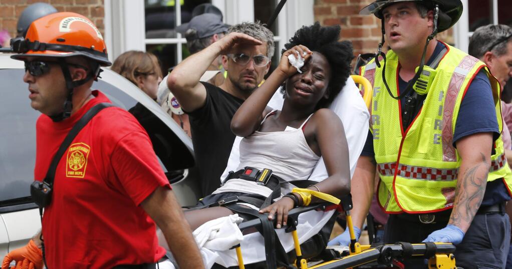 Rescue personnel help an injured woman after a car ran into a large group of protesters after an white nationalist rally in Charlottesville, Va., Saturday, Aug. 12, 2017. The nationalists were holding the rally to protest plans by the city of Charlottesville to remove a statue of Confederate Gen. Robert E. Lee. There were several hundred protesters marching in a long line when the car drove into a group of them.(AP Photo/Steve Helber)