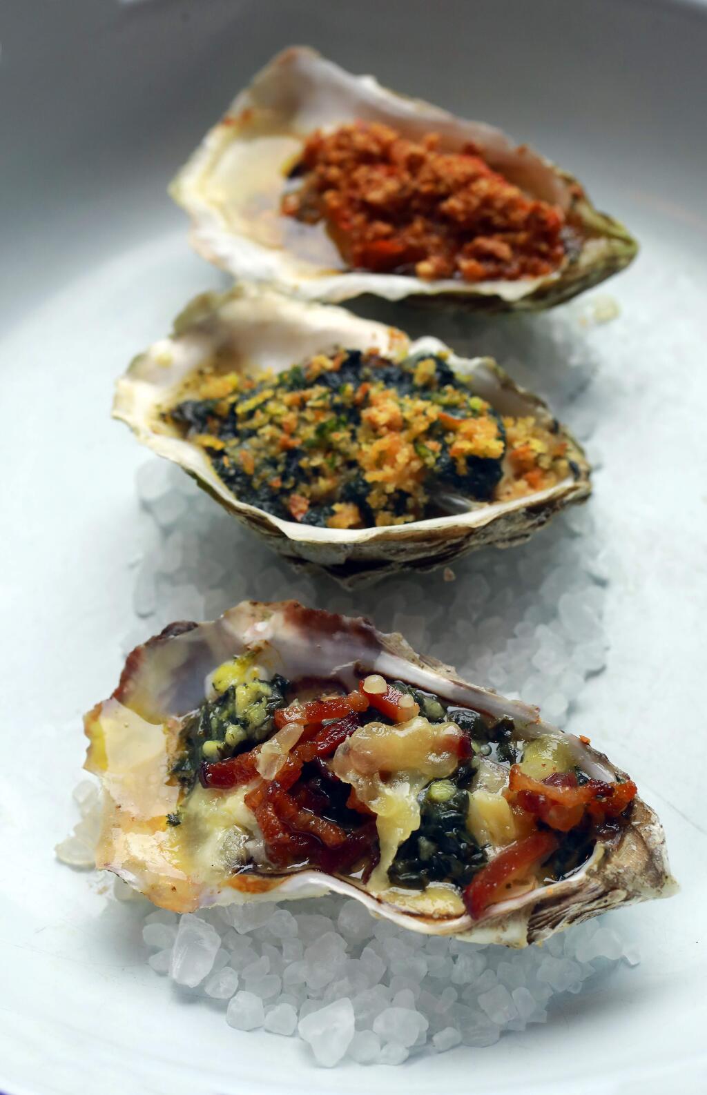 From bottom, the Handline grilled oyster menu includes: the 'Alta CA' with bacon, wilted greens, garlic, St. Jorge, the 'Hwy 1' topped with stinging nettle butter, lemon & parsley gremolata and the 'La Roja'includes mole, garlic butter and toasted almonds,. (John Burgess/The Press Democrat)