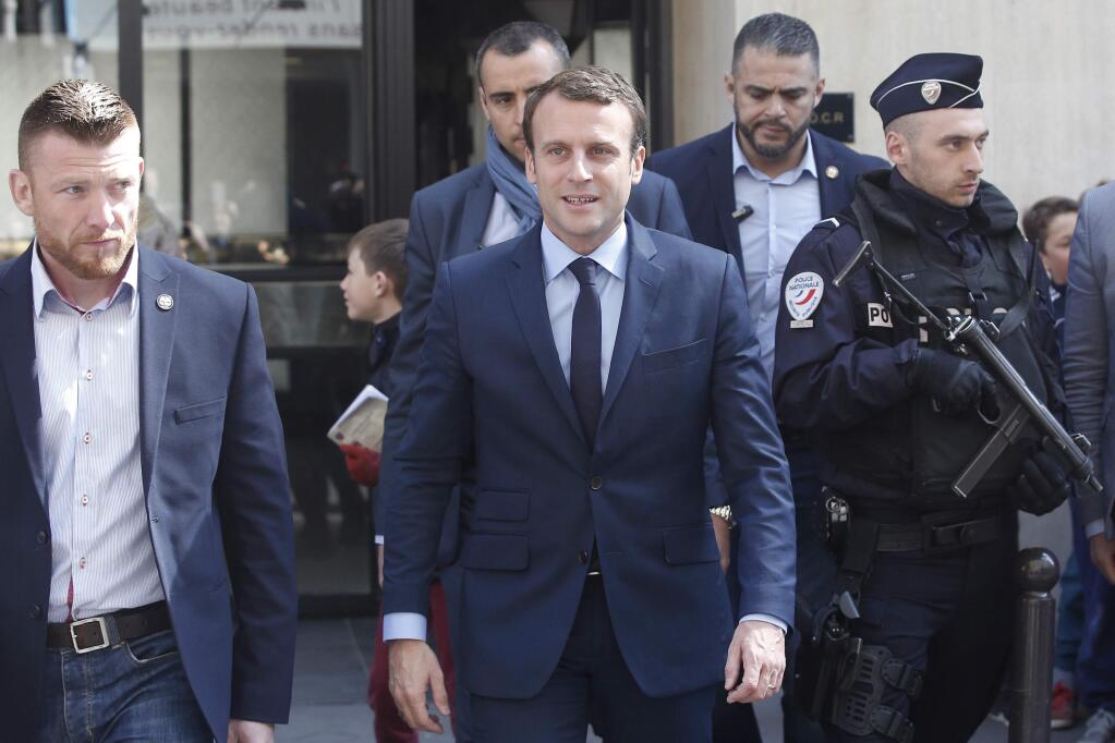 French centrist presidential candidate Emmanuel Macron, center, leaves his apartment, in Paris, Monday, April 24, 2017. French voters shut out the political mainstream from the presidency for the first time in modern history, and on Monday found themselves being courted for the runoff election between populist Marine Le Pen and centrist Emmanuel Macron.(AP Photo/Thibault Camus)