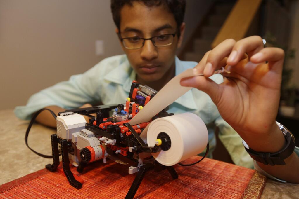 Shubham Banerjee works on his lego robotics braille printer at home Tuesday, Jan. 6, 2015, in Santa Clara, Calif. Banerjee launched a company to develop a low-cost machine to print Braille materials for the blind. It's based on a prototype he built with his Lego robotics kit for a school science fair project. Last month, tech giant Intel Corp. invested in his startup, Braigo Labs, making the 8th grader the youngest entrepreneur to receive venture capital funding. (AP Photo/Marcio Jose Sanchez)
