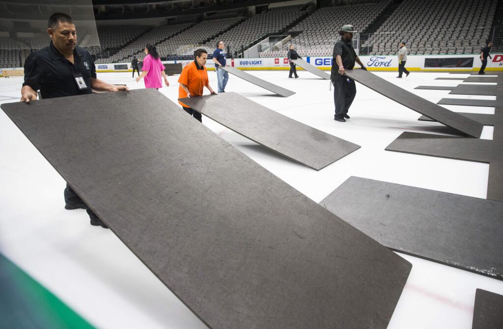 Crews cover the ice at American Airlines Center in Dallas, home of the Dallas Stars, after the NHL season was put on hold due to coronavirus, Thursday, March 12, 2020. (Ashley Landis/The Dallas Morning News via AP)