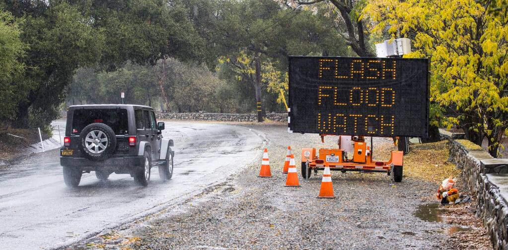 A car passes by a sign warning area residents of a flash flood warning along Trabuco Canyon Road in Trabuco Canyon, Calif., on Thursday morning, Nov. 29, 2018, as heavy rain and storms moved through Orange County and Southern California. (Mark Rightmire/The Orange County Register via AP)