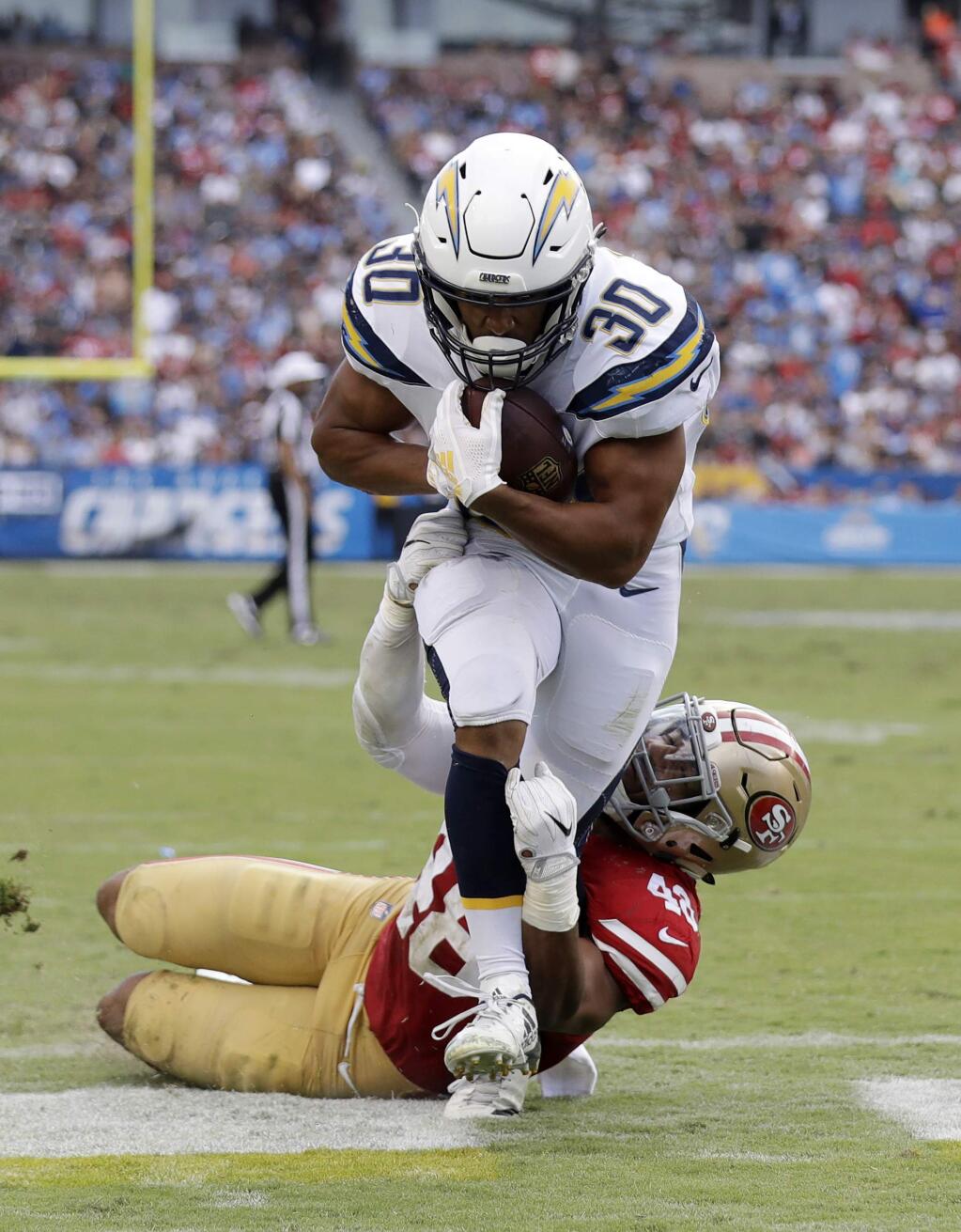 Los Angeles Chargers running back Austin Ekeler, top, runs in for a touchdown as San Francisco 49ers linebacker Fred Warner tries to tackle him during the first half Sunday, Sept. 30, 2018, in Carson. (AP Photo/Marcio Sanchez)
