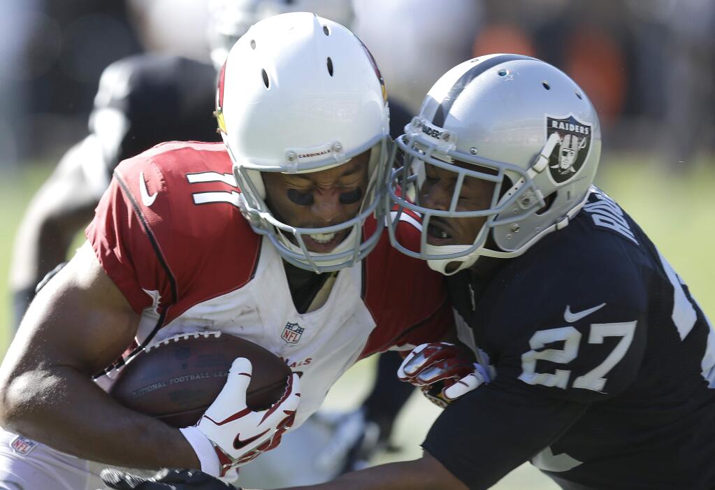 Arizona Cardinals wide receiver Larry Fitzgerald (11) is tackled by Oakland Raiders cornerback Carlos Rogers (27) during the third quarter of an NFL football game in Oakland, Calif., Sunday, Oct. 19, 2014. (AP Photo/Ben Margot)