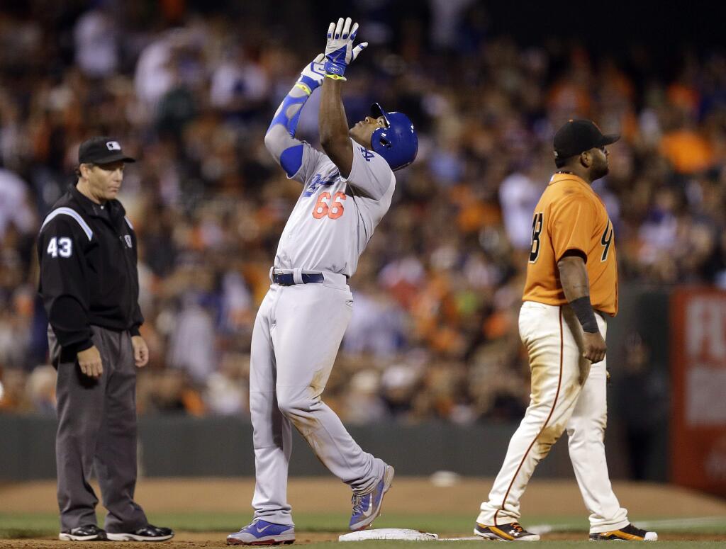 Los Angeles Dodgers' Yasiel Puig (66) celebrates at third base after hitting an RBI triple against the San Francisco Giants in the sixth inning of a baseball game Friday, July 25, 2014, in San Francisco. At left is third base umpire Paul Schrieber, and at right Giants third baseman Pablo Sandoval. (AP Photo)