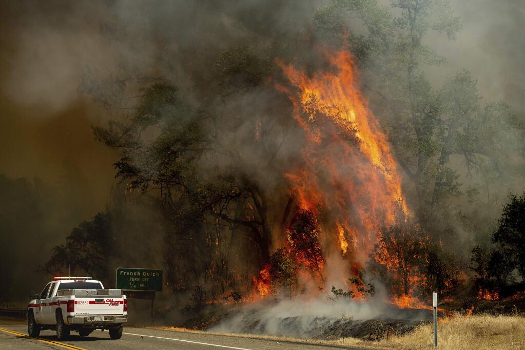 Flames from the Carr Fire lick above a Cal Fire truck in Whiskeytown, Calif., on Friday, July 27, 2018. (AP Photo/Noah Berger, File)