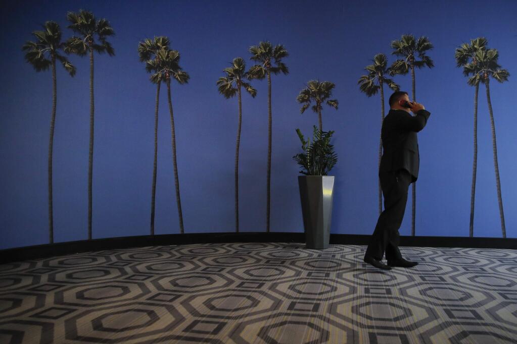 FILE - In this May 4, 2018, file photo a man talks on the phone in a hallway adorned with the palm tree-printed wallpaper at a hotel near the Los Angeles International Airport in Los Angeles. U.S. regulators are proposing new measures intended to thwart billions of annoying robocalls received by Americans each year. The rising volume of unwanted calls in the last few years has created pressure on Congress, regulators and phone companies to do something to act. (AP Photo/Jae C. Hong, File)