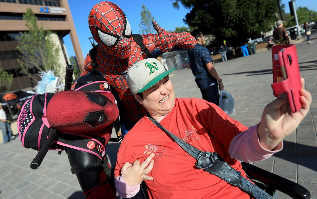 Deadpool character Simeon van Gerpen, left, of Healdsburg and Spider-Man Kyle Baxter of Santa Rosa with Hope Love and Magic, have their photo taken by Stephanie Hulbert during the Wednesday Night Market in downtown Santa Rosa on Wednesday, May 2, 2018. (KENT PORTER/ PD)