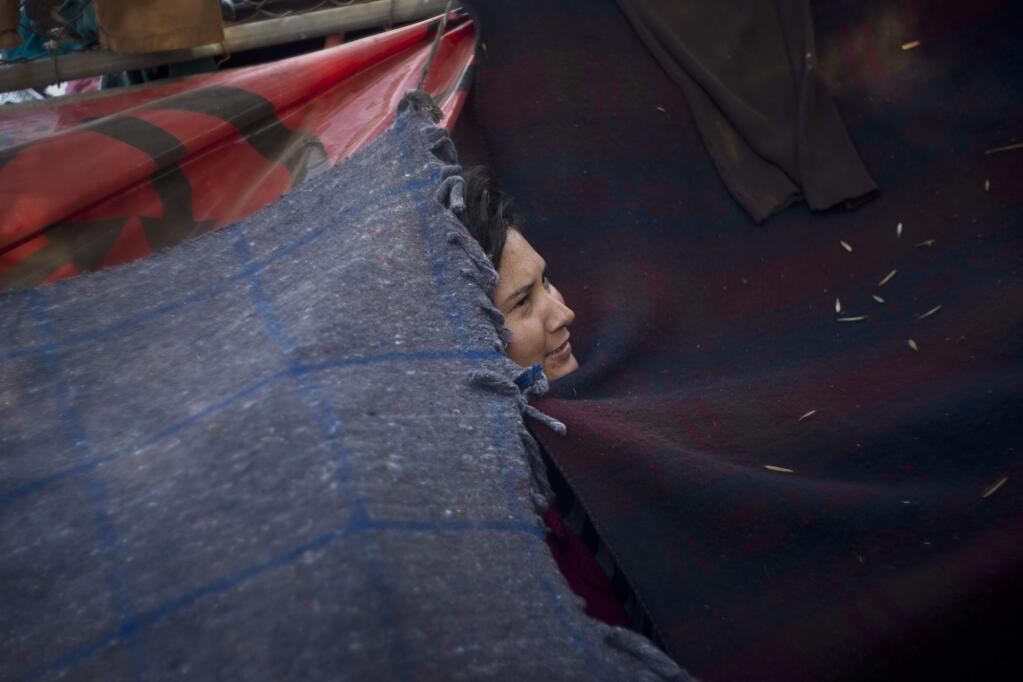 A woman who is part of the migrant caravan, looks out of her tent in Tijuana, Mexico, Wednesday, Nov. 21, 2018. Migrants camped in Tijuana after traveling in a caravan to reach the U.S are weighing their options after a U.S. court blocked President Donald Trump's asylum ban for illegal border crossers. (AP Photo/Ramon Espinosa)