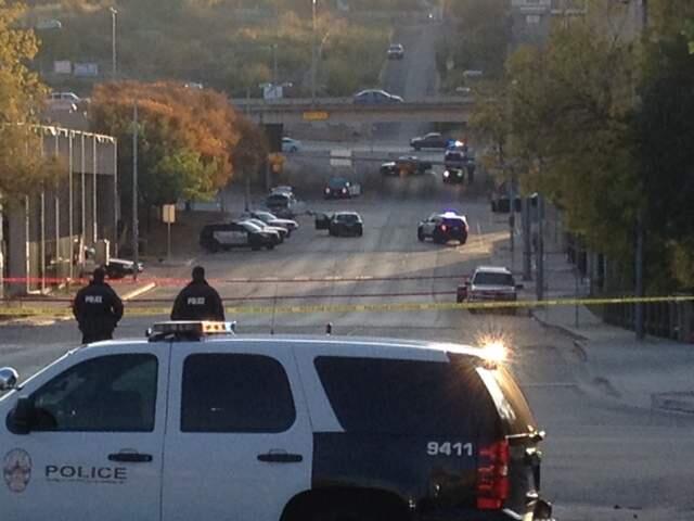 Police tape marks off the scene after authorities shot and killed a man who they say opened fire on the Mexican Consulate, police headquarters and other downtown buildings early Friday, Nov. 28, 2014, in Austin, Texas. In the distance, police cars surround the suspect's vehicle parked near the Interstate 35 overpass. (AP Photo/Jim Vertuno)