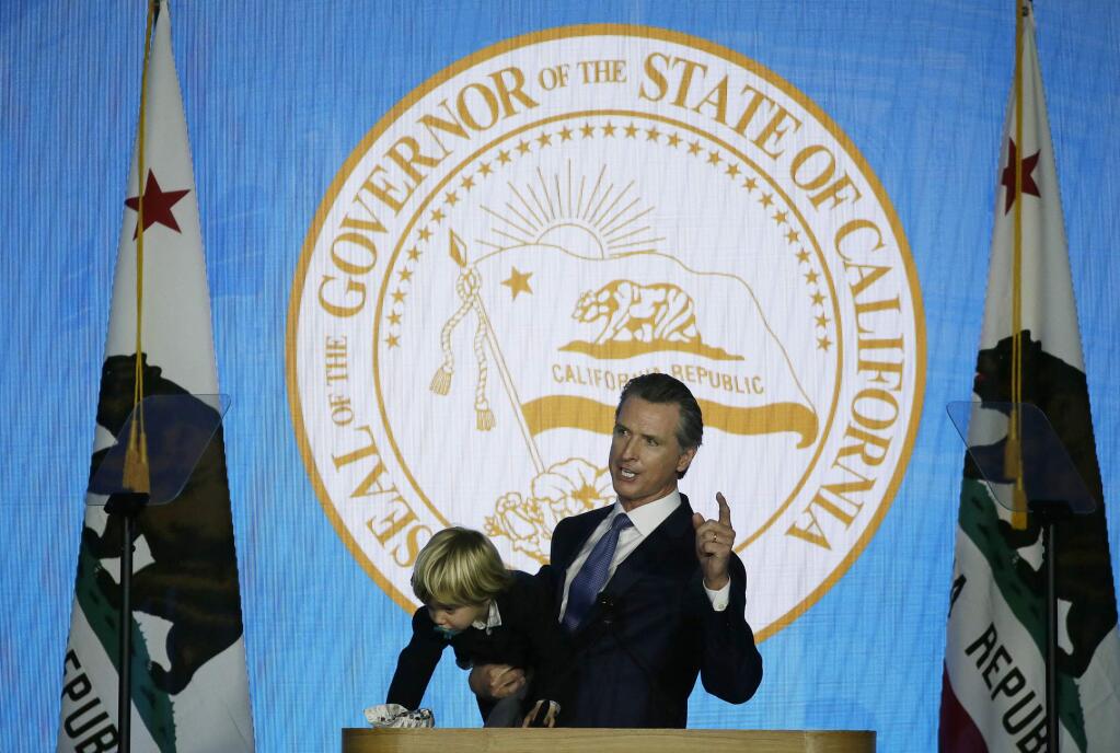 In this Monday, Jan. 7, 2019, photo, California Gov. Gavin Newsom holds his son Dutch while giving his address at his inauguration in Sacramento, Calif. Newsom gets his chance this week to show how he'll resolve a central tension in his platform: advancing expensive new programs while maintaining robust savings. (AP Photo/Eric Risberg)