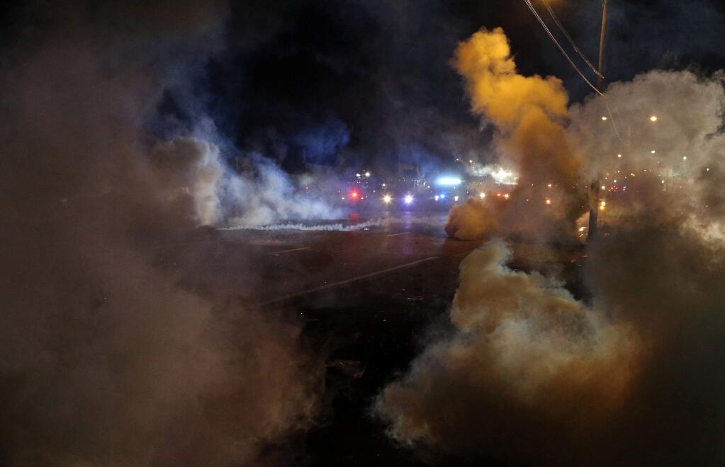 Tactical trucks move down the street through tear gas in Ferguson, Mo., Sunday, Aug. 17, 2014. (AP Photo/St. Louis Post-Dispatch, J.B. Forbes)