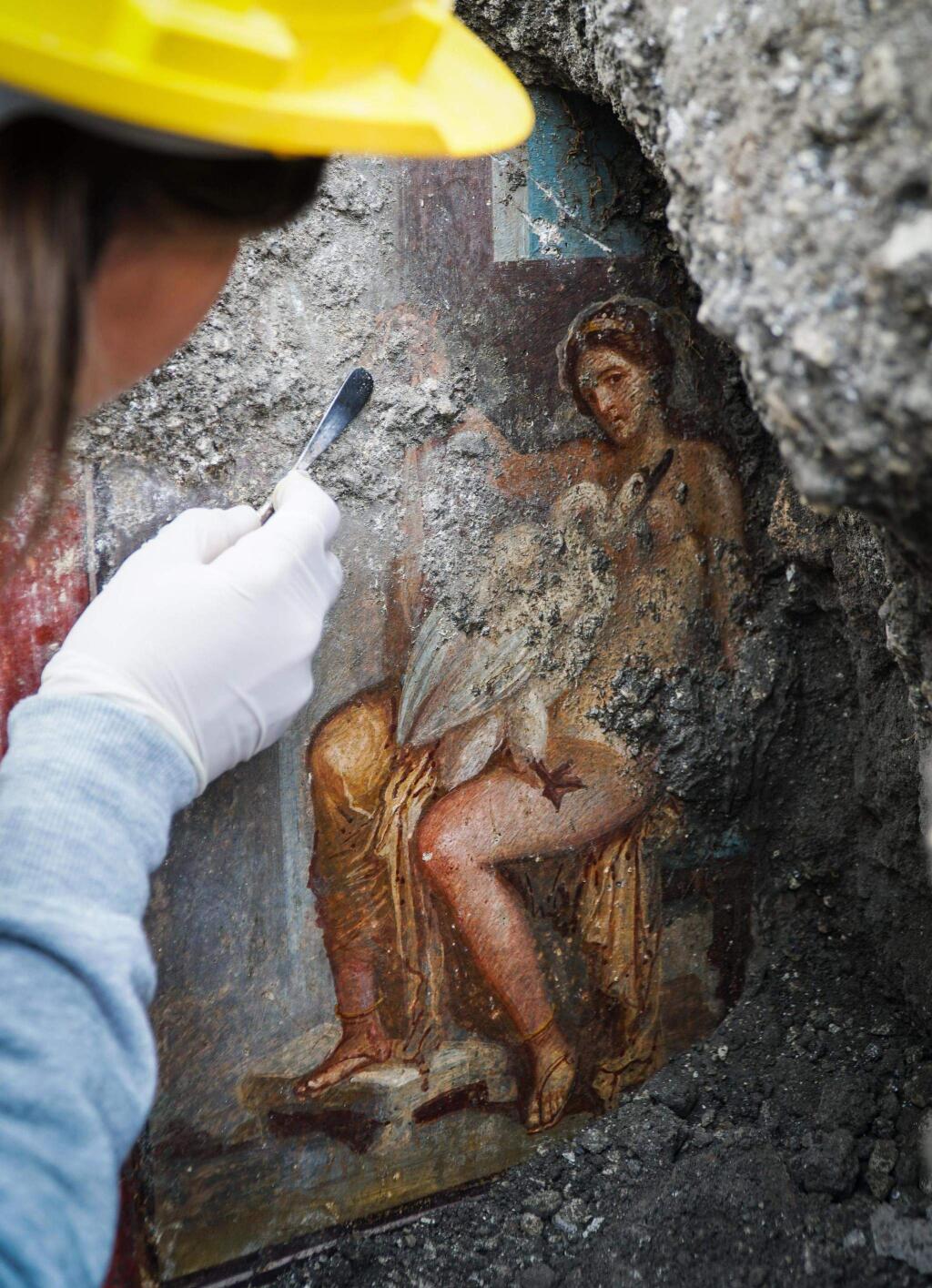 An archeologist cleans up the fresco ''Leda e il cigno'' (Leda and the swan) discovered last Friday in the Regio V archeological area in Pompeii, near Naples, Italy, Monday, Nov. 19, 2018. The fresco depicts a story and art subject of Greek mythology, with Queen of Sparta Leda being impregnated by Zeus - Jupiter in Roman mythology - in the form of a swan. (Cesare Abbate/ANSA via AP)