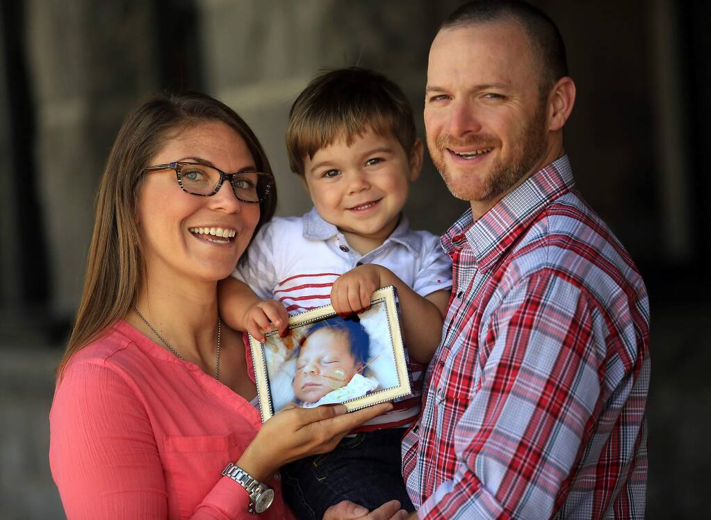 PHOTO: 1 by JOHN BURGESS / The Press Democrat -Amie, Reid, 2, and Chris Lands hold a photo of Reid's sister Ruthie Lou, who died as an infant in 2011. The couple now help other families who lose their babies.