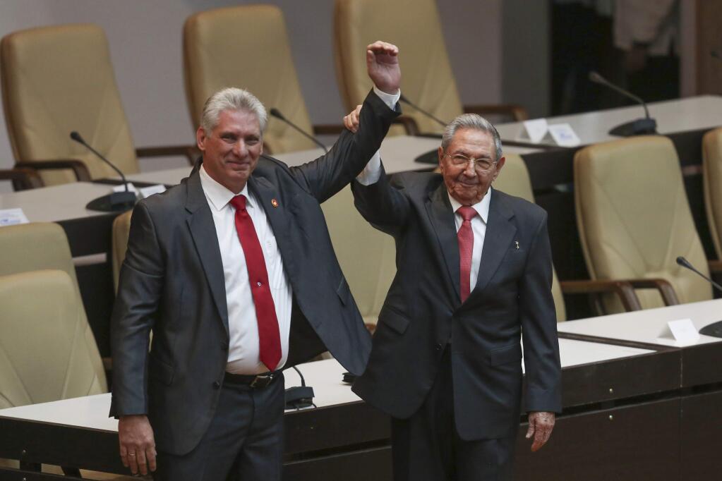 Cuba's new president Miguel Diaz-Canel, left, and former president Raul Castro, raise their arms after Diaz-Canel was elected as the island nation's new president, at the National Assembly in Havana, Cuba, Thursday, April 19, 2018. Castro left the presidency after 12 years in office when the National Assembly approved Diaz-Canel's nomination as the candidate for the top government position. (Alexandre Meneghini/Pool via AP)
