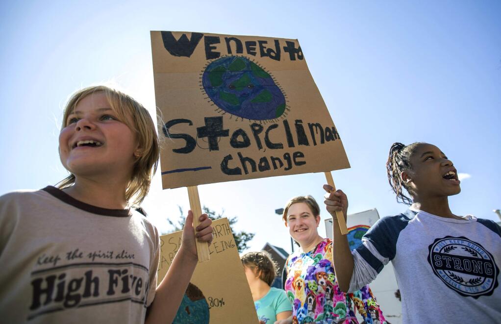 Haley Williams, left, and Amiya Cox hold a sign together and chant while participating in a 'Global Climate Strike' at the Experiential School of Greensboro in Greensboro, N.C., on Friday, Sept. 20, 2019. The United Nations Panel on Climate Change  concluded that because nations have waited so long to curb emissions, average global temperatures will further rise to 1.5 degrees Celsius within the next 20 years. (KHADEJEH NIKOUYEH/NEWS & RECORD VIA THE ASSOCIATED PRESS)