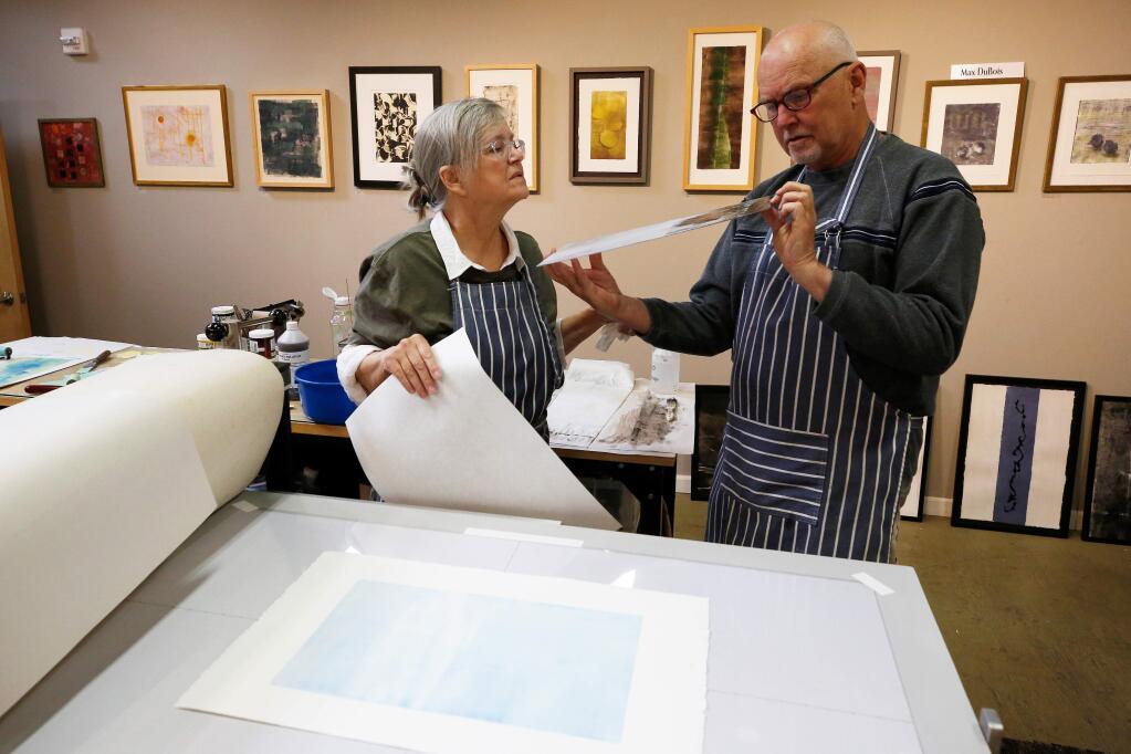 Mixed media artists Max Dubois, left, and Gary Morgret examine the results of a monotype transfer that Morgret just ran through the print-making press at their shared art studio in the SOFA arts district of Santa Rosa, California, on Thursday, May 9, 2019. (Alvin Jornada / The Press Democrat)
