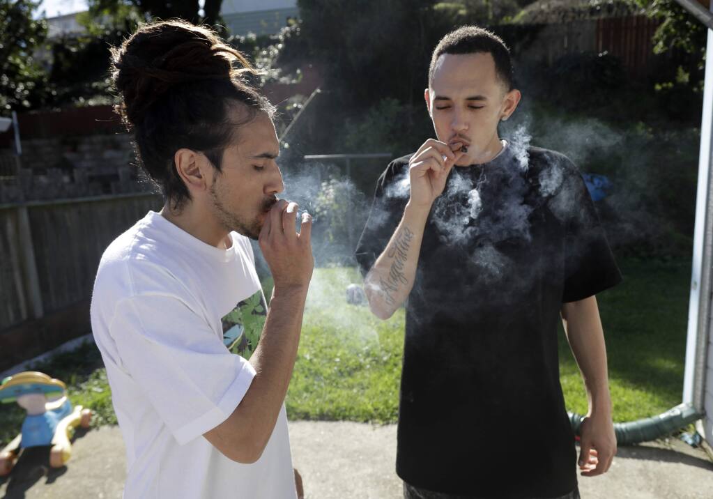 FILE- In this Nov. 9, 2016 file photo, Dave Jimenez, left, smokes marijuana with his friend Anthony A. in San Francisco. California law enforcement officials objected Wednesday, April 5, 2017, to Gov. Jerry Brown's proposed streamlining of the state's marijuana regulations, saying his plan could endanger public safety. Brown's administration released documents late Tuesday outlining proposed changes to square the state's new recreational pot law with its longstanding law on medical marijuana. (AP Photo/Marcio Jose Sanchez, File)