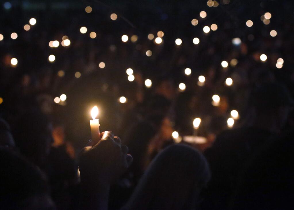 FILE - In this Thursday, Feb. 15, 2018, file photo, attendees hold up their candles at a candlelight vigil for the victims of the shooting at Marjory Stoneman Douglas High School, in Parkland, Fla. A Florida law that allows judges to bar anyone deemed dangerous from possessing firearms has been used 3,500 times since its enactment after the 2018 high school massacre. An Associated Press analysis shows the law is being used unevenly around the state. (AP Photo/Wilfredo Lee, File)