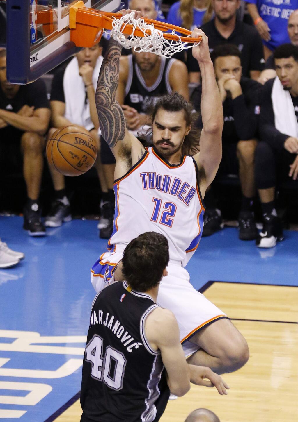 Oklahoma City Thunder center Steven Adams (12) dunks over San Antonio Spurs center Boban Marjanovic (40) in the second quarter of Game 6 of a second-round series in Oklahoma City, Thursday, May 12, 2016. (AP Photo/Alonzo Adams)