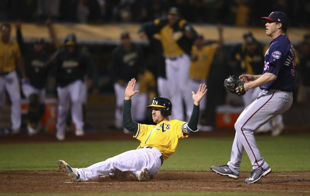 Oakland Athletics' Stephen Piscotty slides to score in front of Minnesota Twins' Trevor Hildenberger in the ninth inning of a baseball game Saturday, Sept. 22, 2018, in Oakland, Calif. Piscotty scored on a walk-off wild pitch by Hildenberger. (AP Photo/Ben Margot)