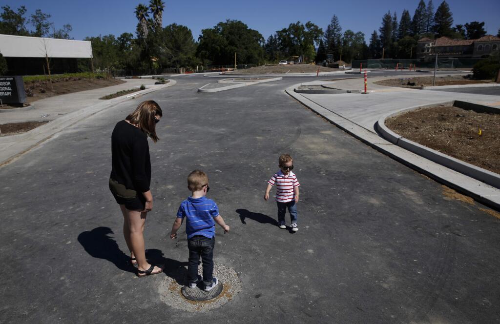 Kristi Spaulding walks with her sons Jayden, 4, and Hudson, 2, as they check out a roundabout under construction at the intersection of Old Redwood Hwy and Market St. on Sunday, March 29, 2015 in Windsor, California . (BETH SCHLANKER/ The Press Democrat)