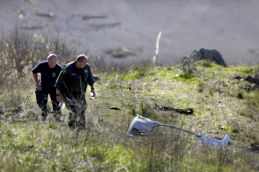 Emergency workers look over debris at the scene of a fatal car crash off Highway 1, about 5 miles north of Jenner on Tuesday, Dec. 30, 2014. (BETH SCHLANKER/ PD)
