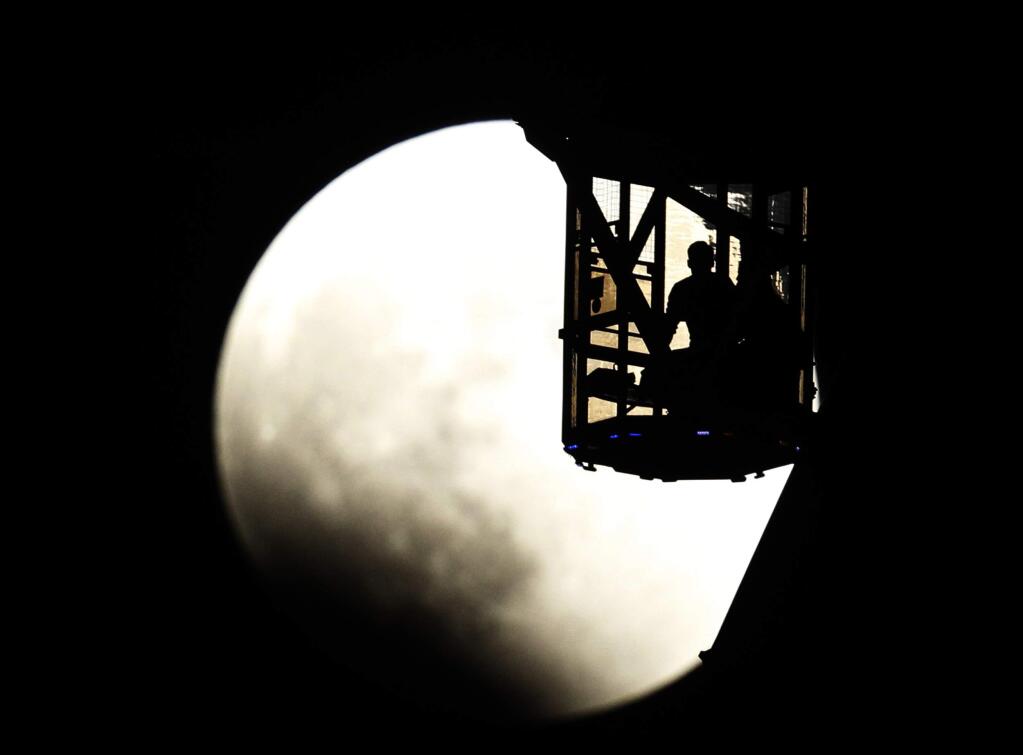 The Earth's shadow renders the moon as a couple in Ferris wheel observe it during a total lunar eclipse in Tokyo, Wednesday, Oct. 8, 2014. (AP Photo/Koji Sasahara)