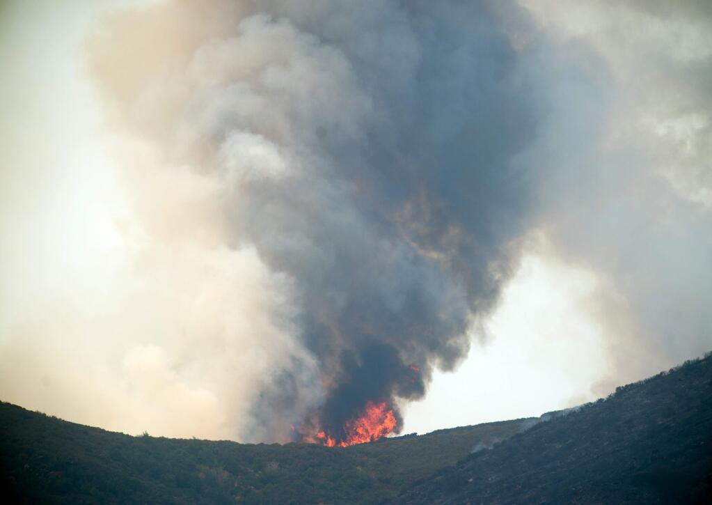 Smoke and flames rise from a ridge top as the Wragg fire burns near Winters, Calif., on Thursday, July 23, 2015. According to Cal Fire, the blaze scorched more than 6,000 acres and is threatening 200 structures. (AP Photo/Noah Berger)